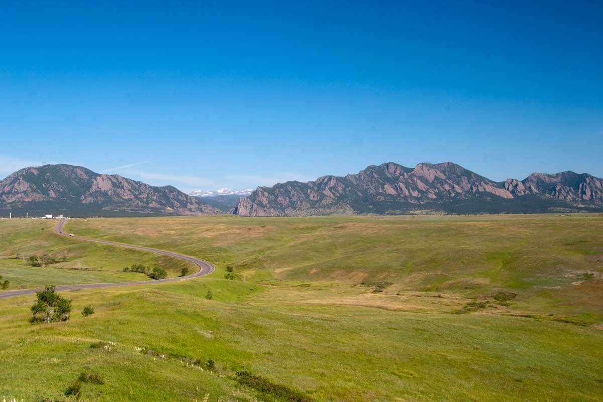 Boulder's famous slanted Flatiron mountains rise above vast, green rolling foothills.