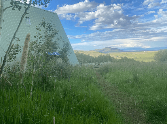 Exterior view of the side of Moose Haven Cabin with blue sky and clouds in the background along with a picnic table
