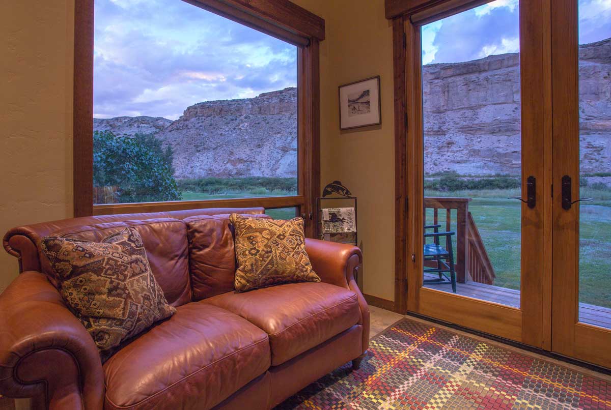 Interior of a Gunnison River Farms cabin with a buttery leather couch and rock formations seen from the large windows