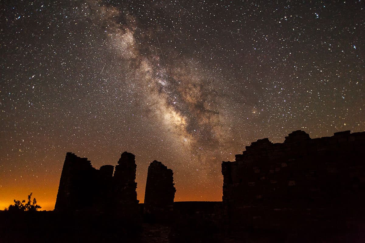 Milky Way formation with hundreds of stars above stone structures at night
