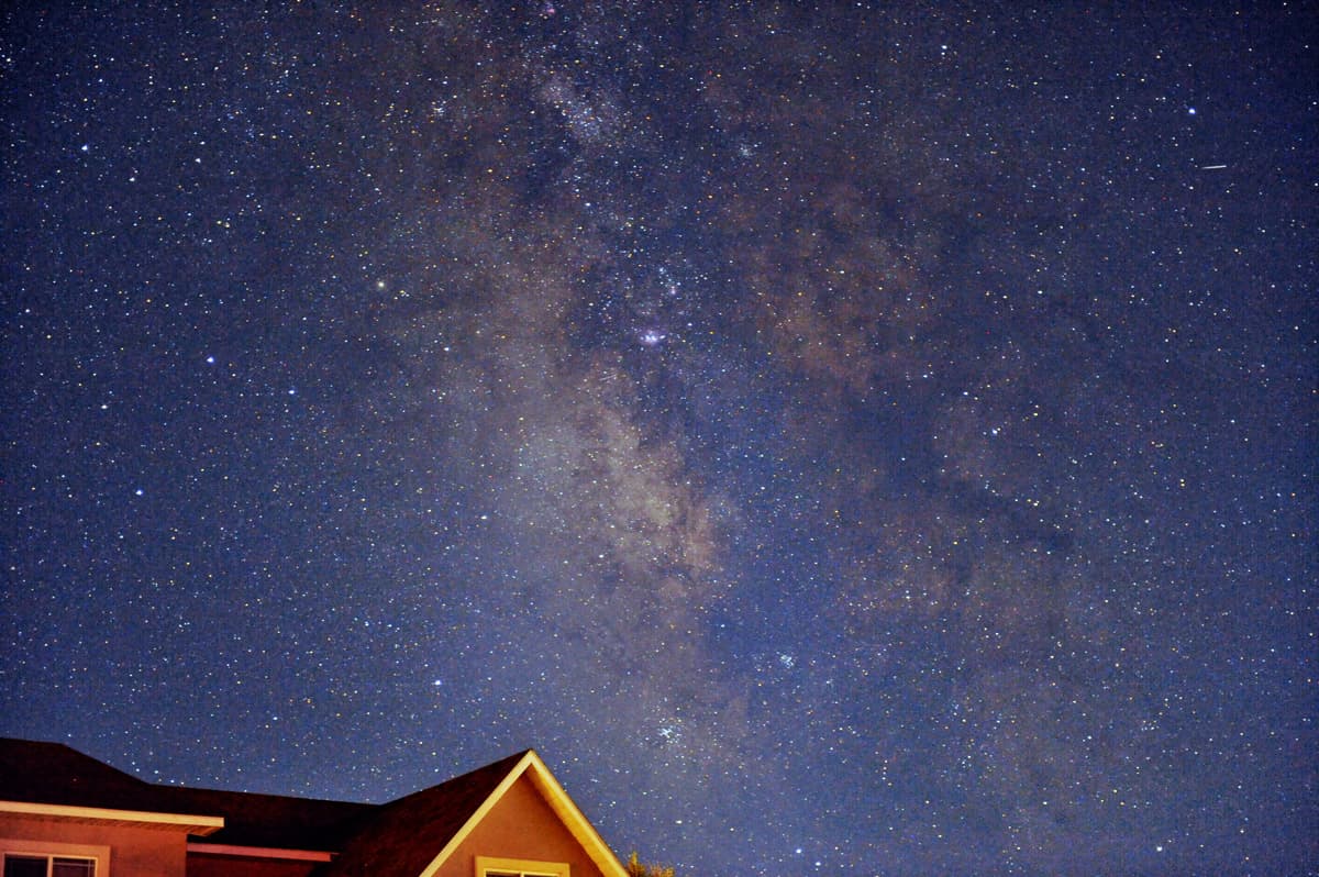 The night sky with twinkling stars sits above a peaked roof.