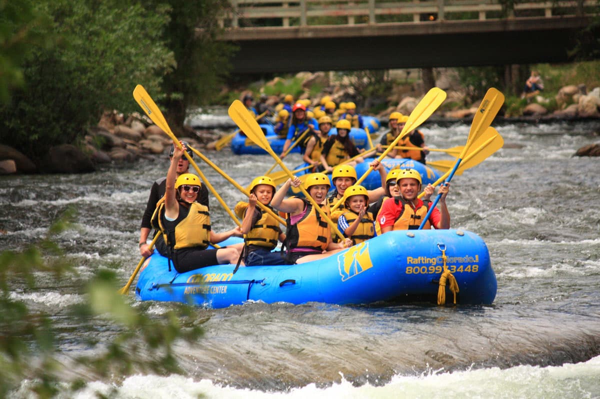Rafters smile and raise their yellow paddles as they approach a set of whitewater rapids on the Clear Creek near Idaho Springs.