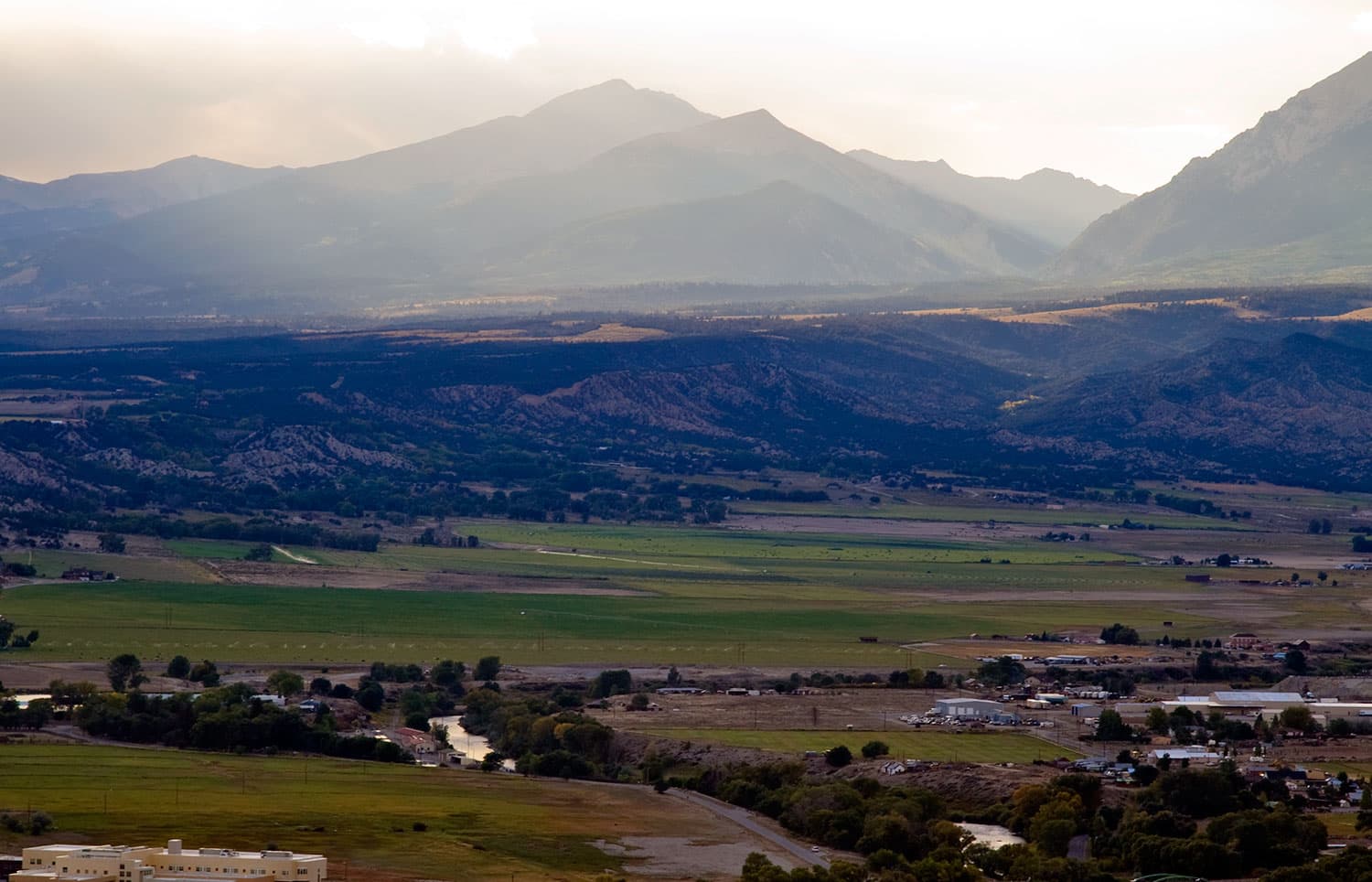 The hazy mountains are in the background and a valley is in the foreground with green farmer fields.