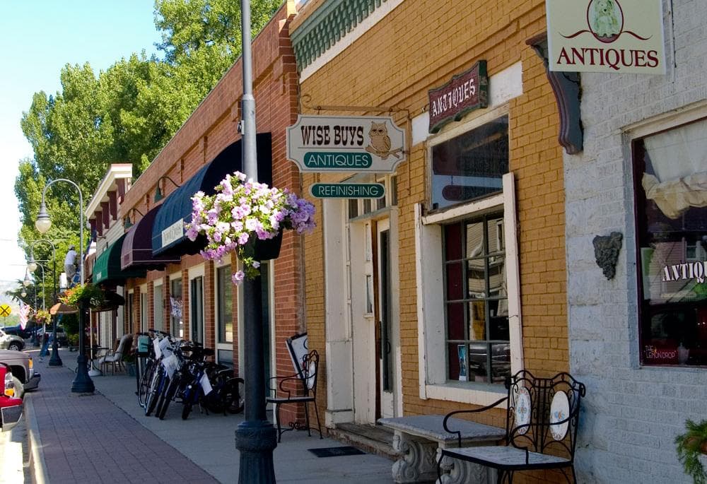 Yellow and red brick antique stores line the sidewalks of downtown Niwot with benches and bikes parked near streetlights.