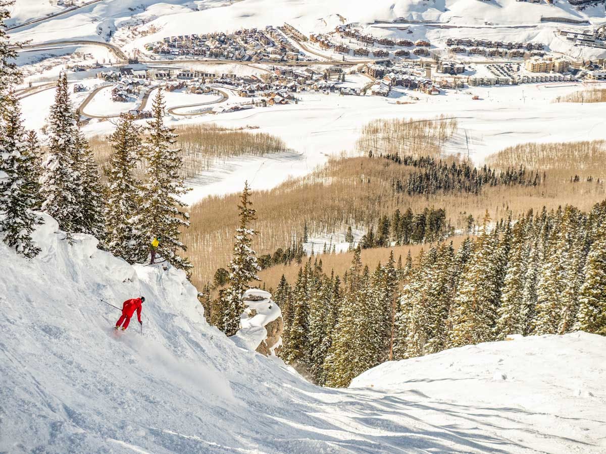 A skier at Crested Butte Mountain Resort with the village in the distance