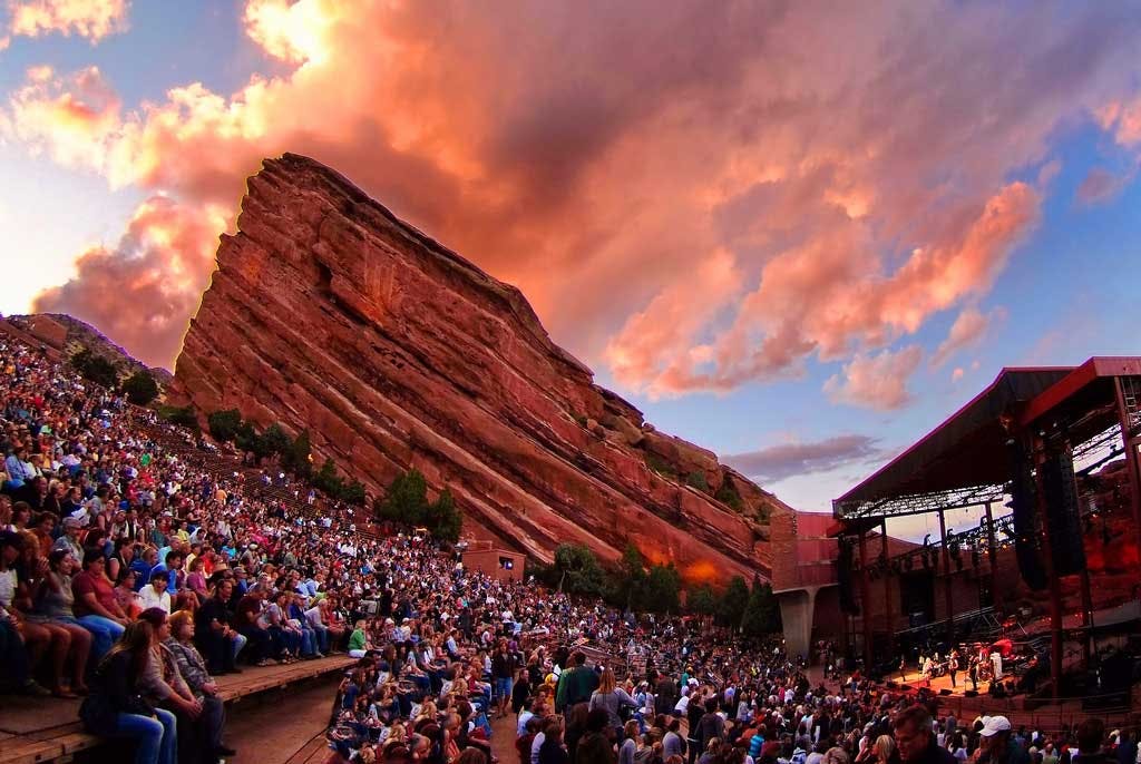 An outdoor concert at a stage surrounded by red-rock mountains