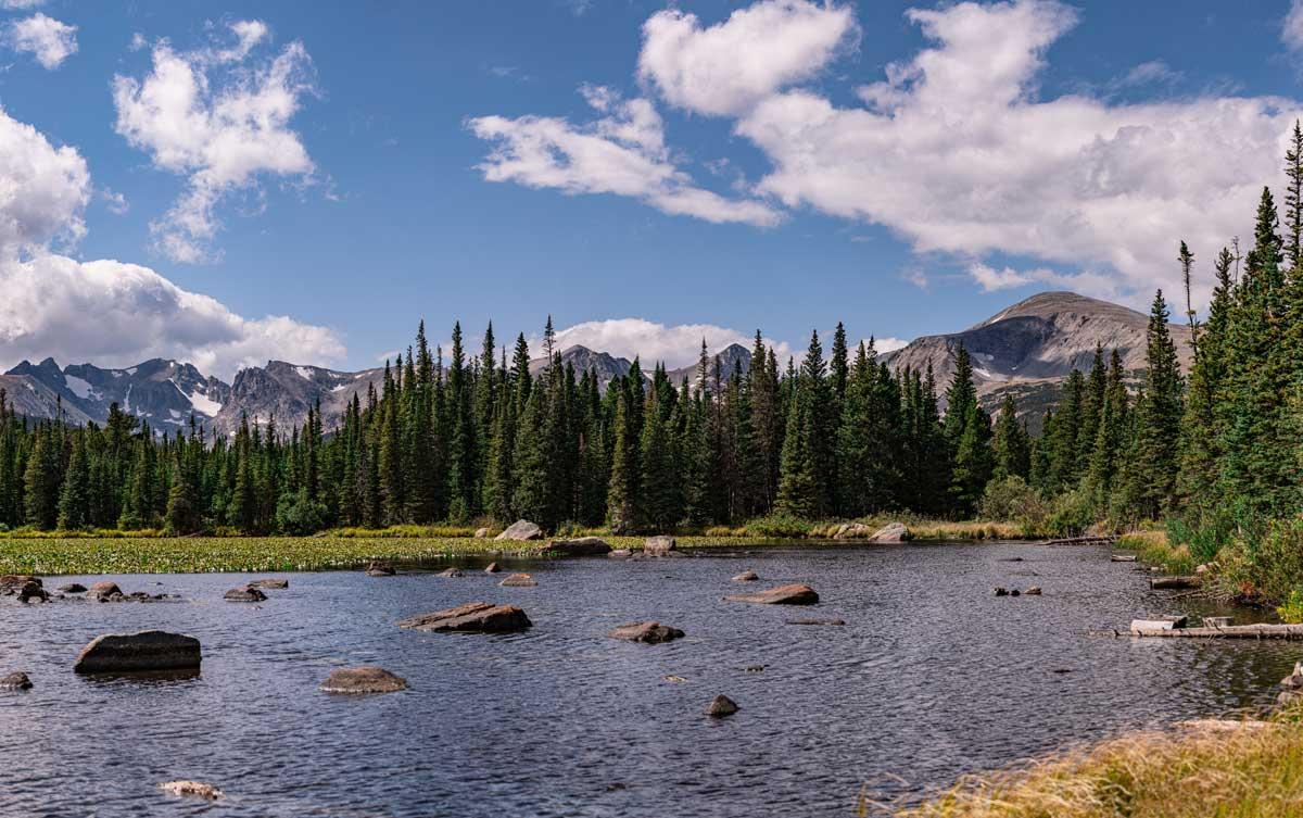 A blue sky dotted with clouds creates a bright sunny, summer day at Brainard Lake Recreation Area near Boulder.