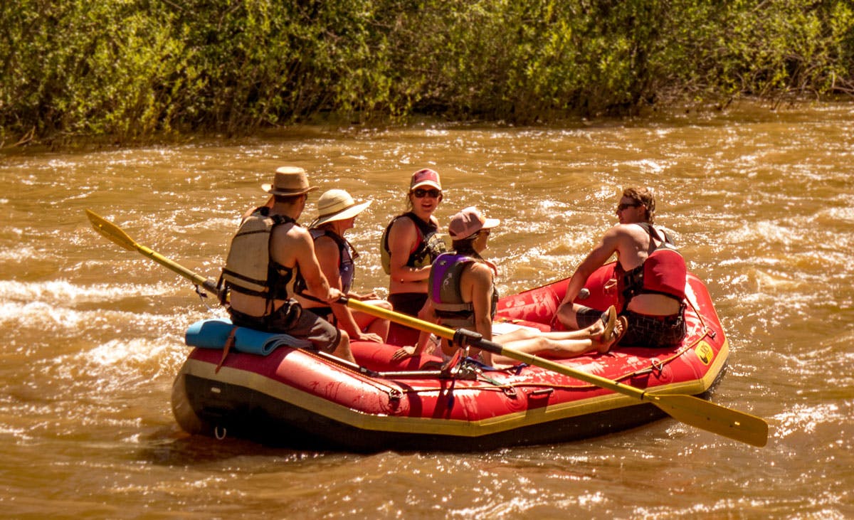 A group of five rafting in a red inflatable raft on Colorado's Dolores River