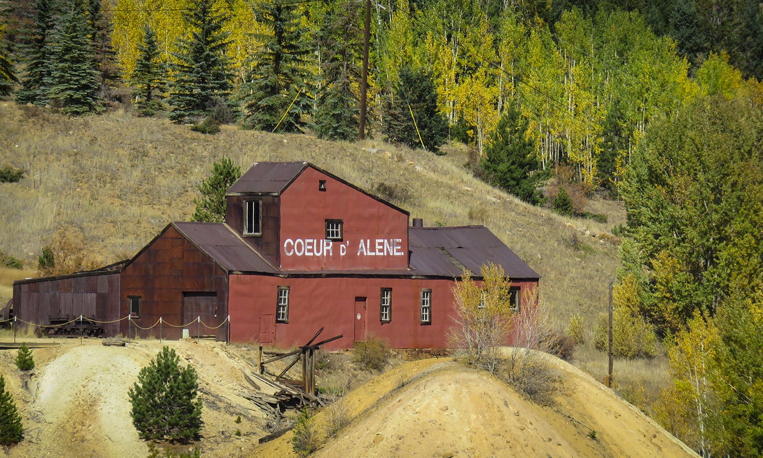 Red-barn Coeur d' Alene Mine surrounded by green trees