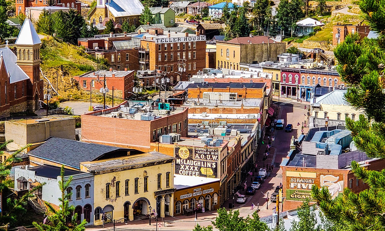 An aerial view of Central City in the summer with green trees, Western storefronts and colorful buildings.