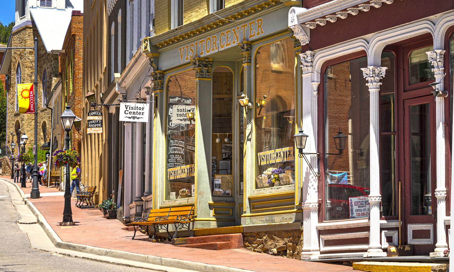 Colorful Western storefronts, with the green Central City Visitor's Center in the middle on a sunny day.