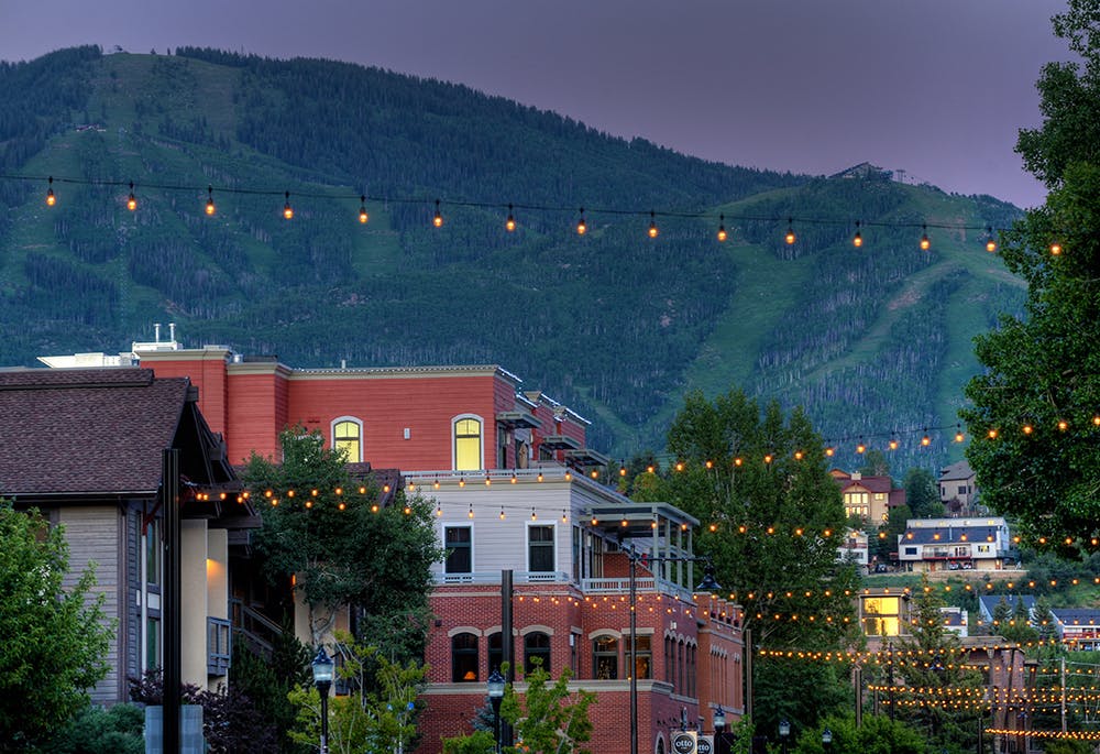 Charming downtown Steamboat Springs at dusk with fairy lights strung over the streets and the mountains in the background