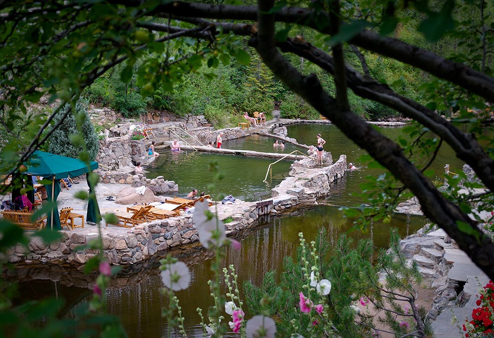 Strawberry Park Hot Springs pools, with people soaking in the pools and lounging on the rocky shores