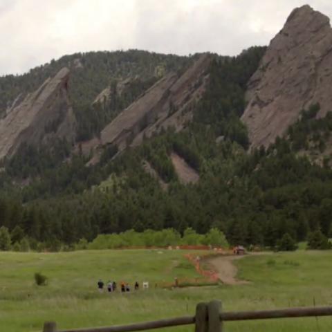 People in the distance walking a trail toward Boulder's Flatirons 