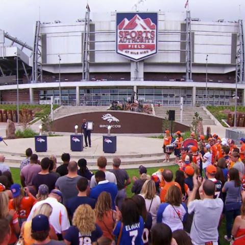 People watching a speaker at a baseball stadium