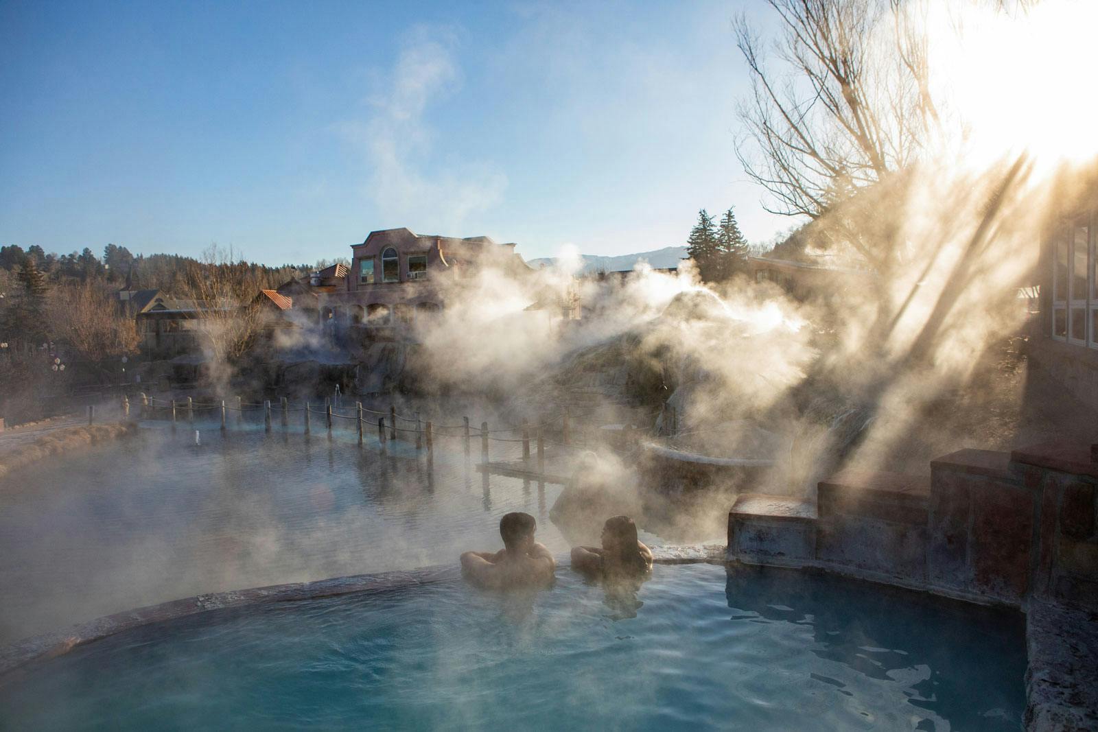 A couple soaks in a hot springs on a foggy winter morning