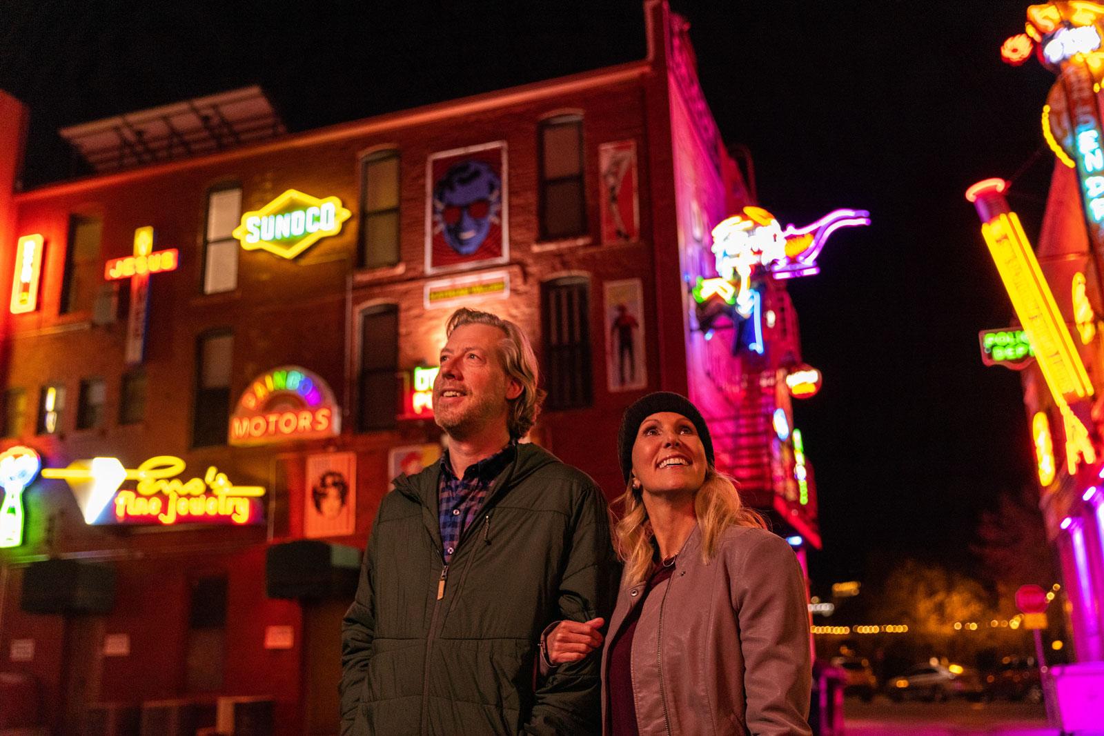 A couple walks through the neon signs of Pueblo's Neon Alley