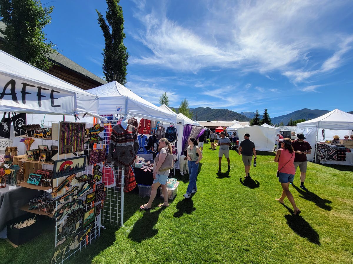 White vendor tents set up at the summer Arts & Crafts Fair in Grand Lake, Colorado, welcome curious visitors inside.