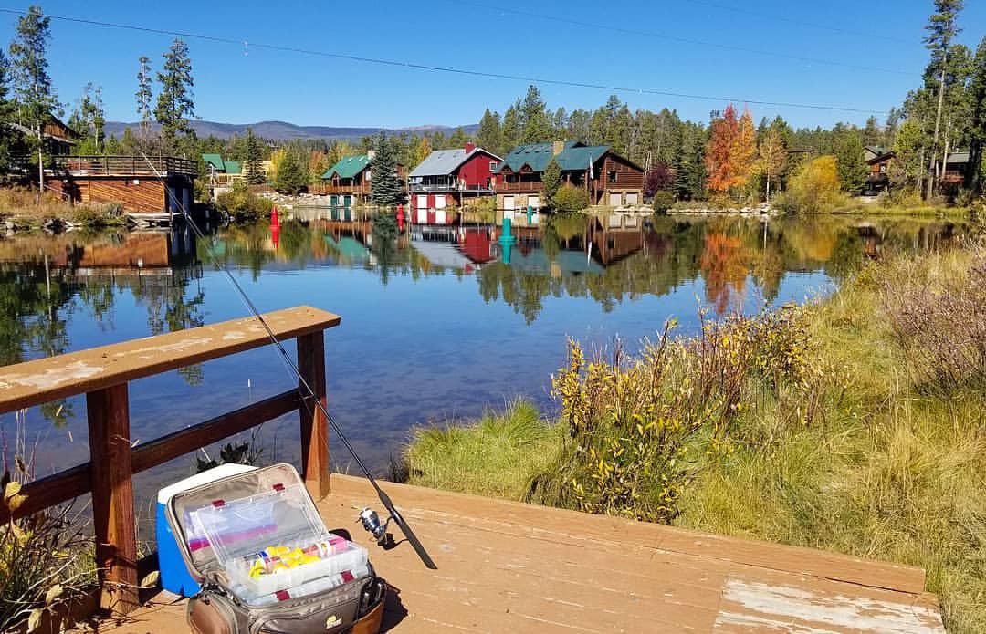 A fishing tackle box and rod and reel sit unattended on a worn, wooden dock at Grand Lake's Point Park in Colorado.