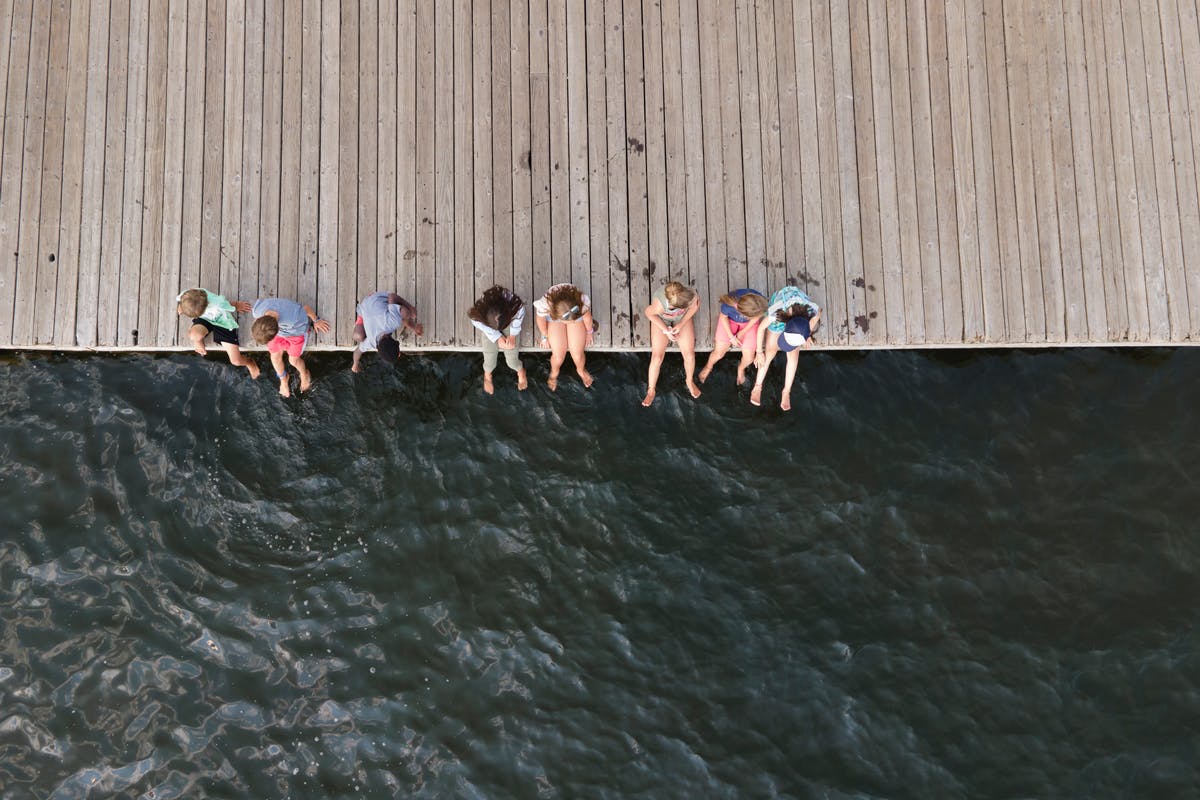 An aerial view shows children sitting on the edge of Town Dock and dangling their feet above the dark water at Grand Lake, Colorado.