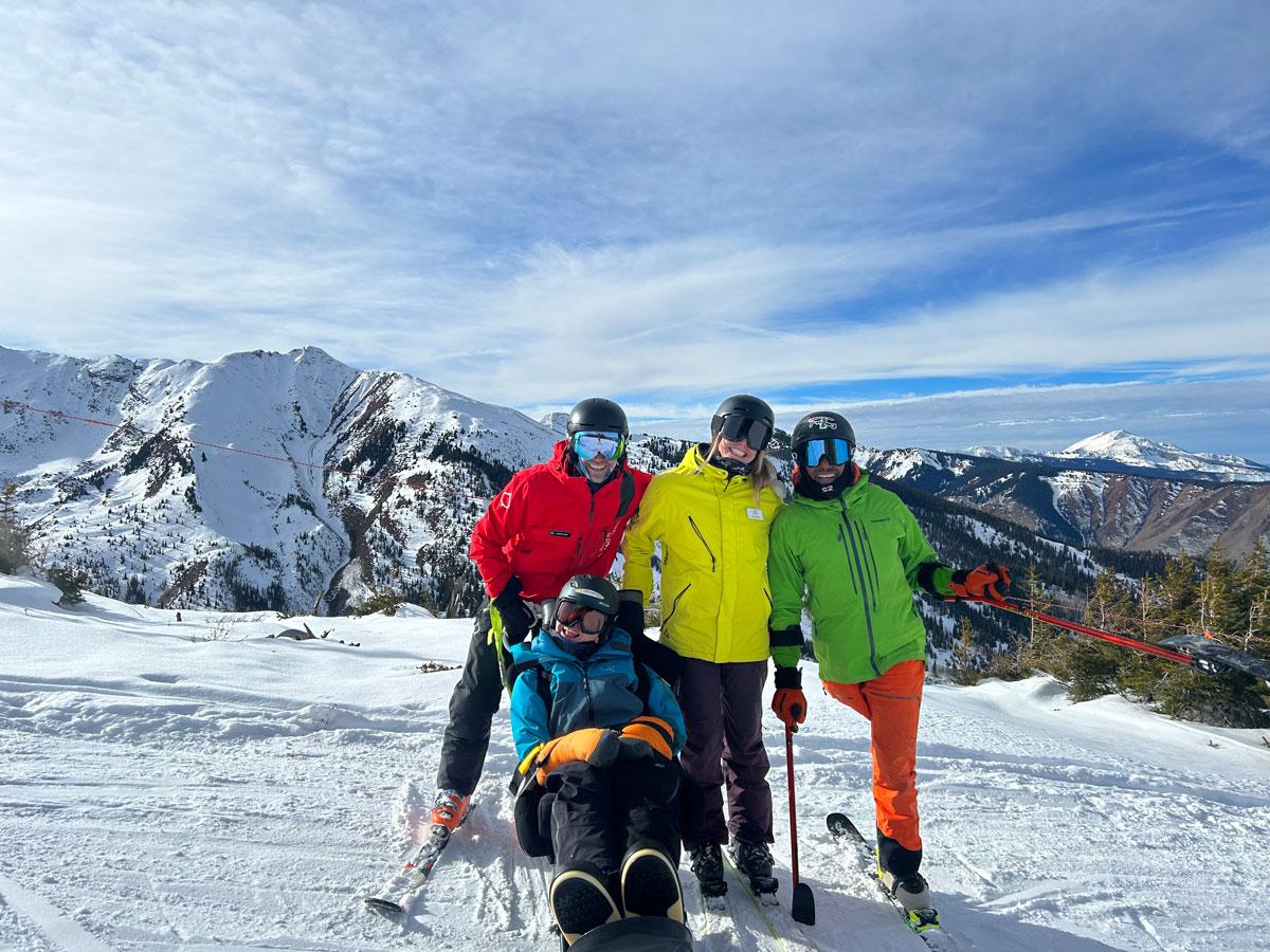 A group of skiers with disabilities and their instructor stand on top of a mountain near Aspen Colorado