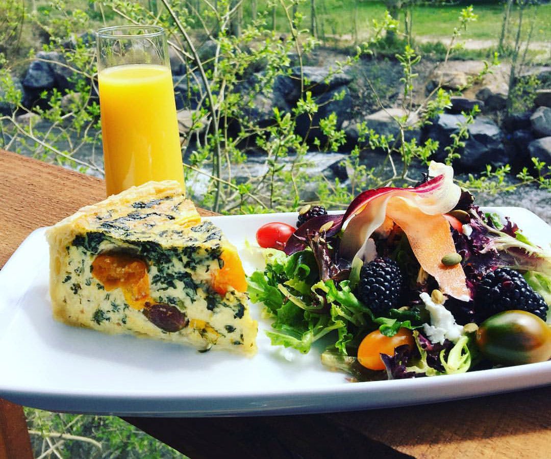 A vegetable quiche, colorful salad with berries and melon, and a glass of orange juice overlooking the waters of Clear Creek.