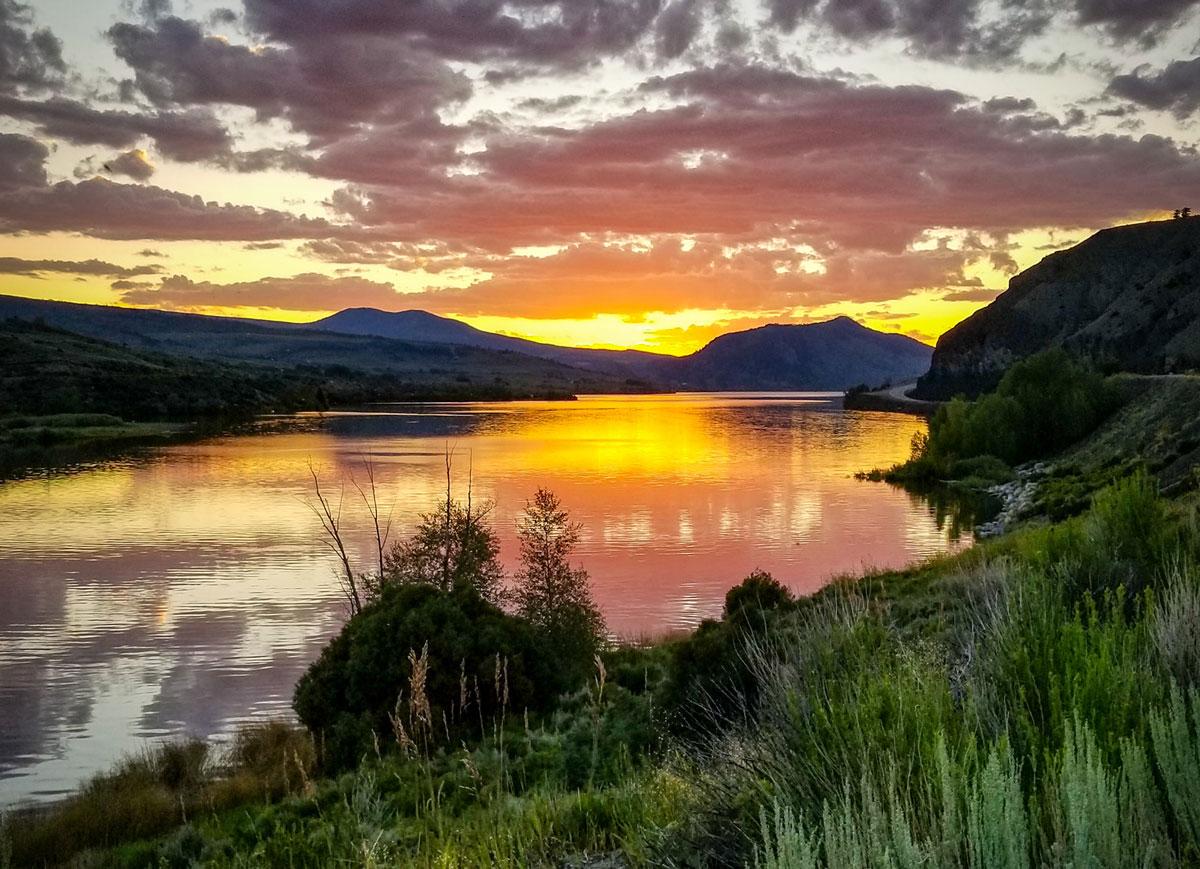 The sherberty colors of sunset reflect in Kremmling's Wolford Mountain Reservoir with mountains in the background