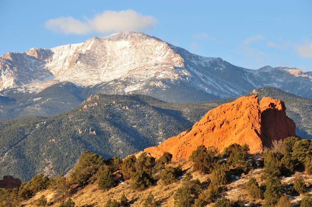 Snowcapped Pikes Peak rises above some of the red rocks and scrub brush of Garden of the Gods