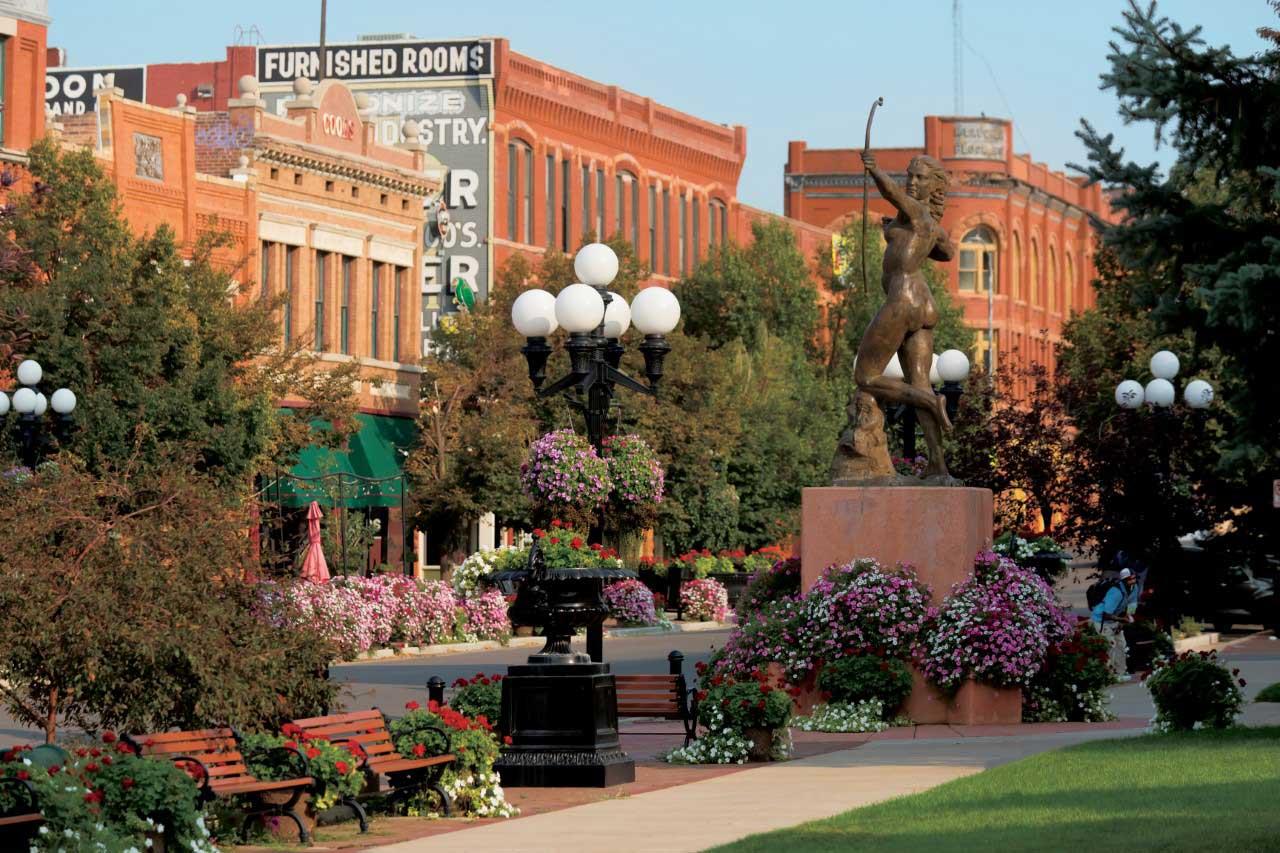 Red-brick buildings stand behind trees and flowerbeds in Downtown Pueblo