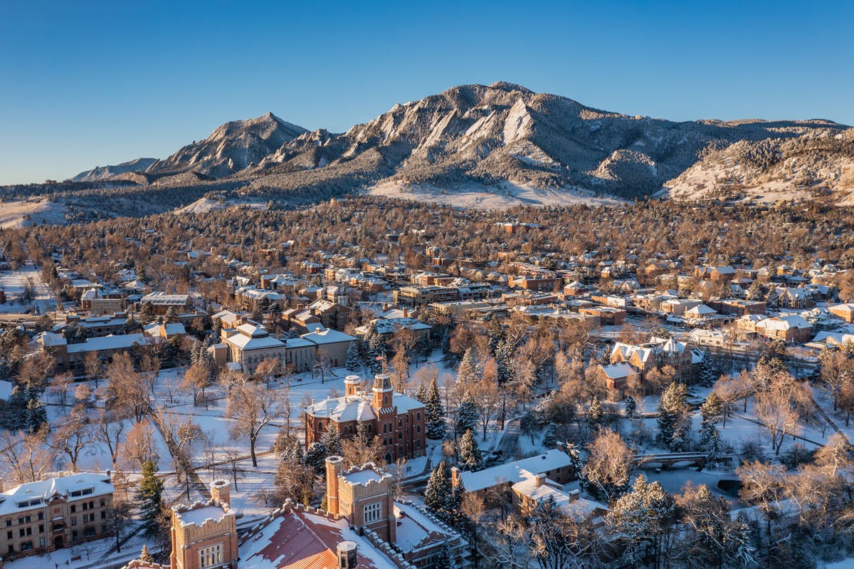 An aerial view of Boulder, Colorado dusted with snow featuring views of Chautaqua Park and the famous Flatirons Mountains.