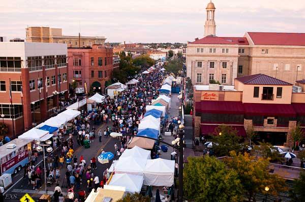 In an aerial view, crowds of people meander down a street between the tent-covered food stalls of the Pueblo Chile & Frijole Festival.