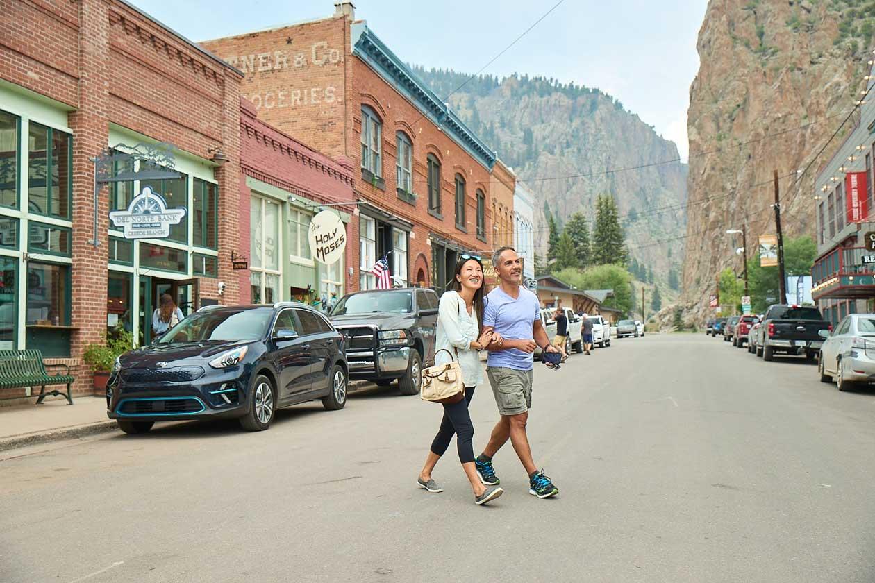 Two people cross a street lined with historical buildings