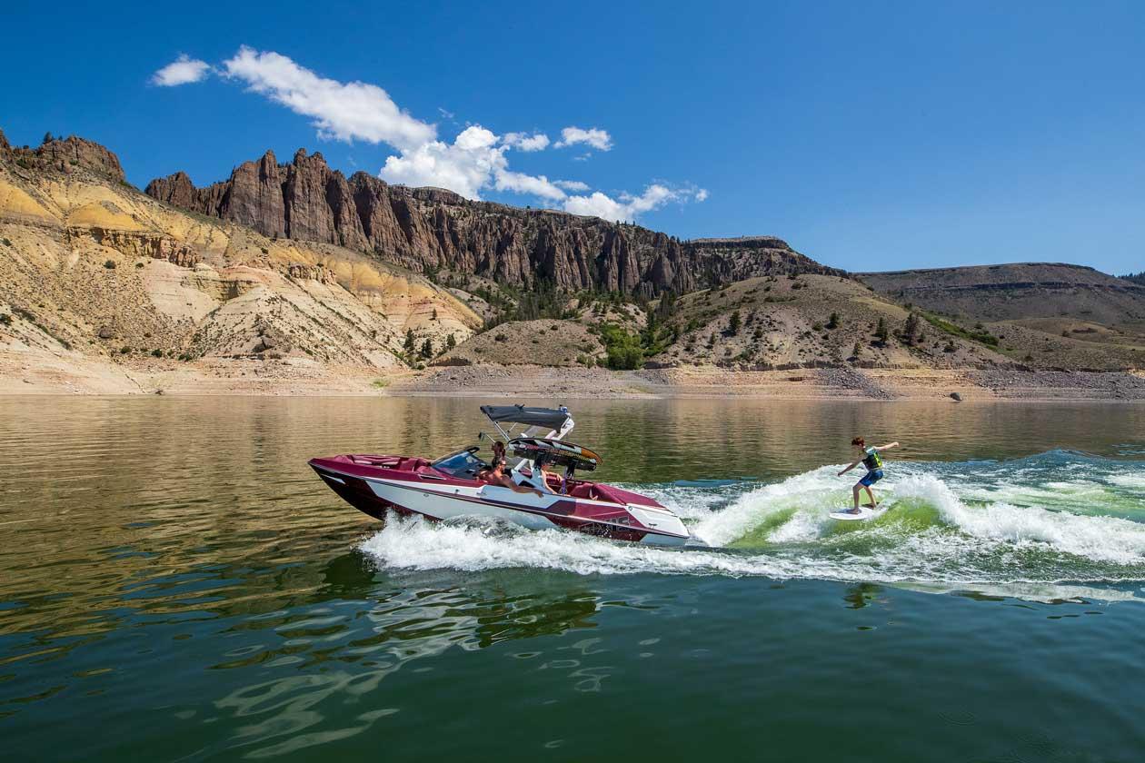 A wake boarding rides waves behind a motor boat