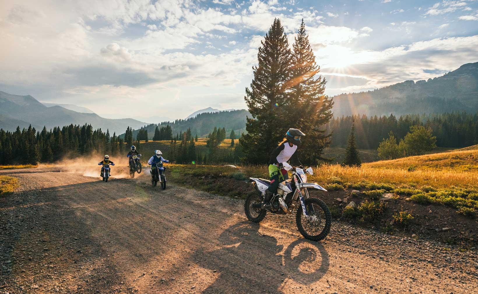 A group rides dirt bikes on a dirt trail