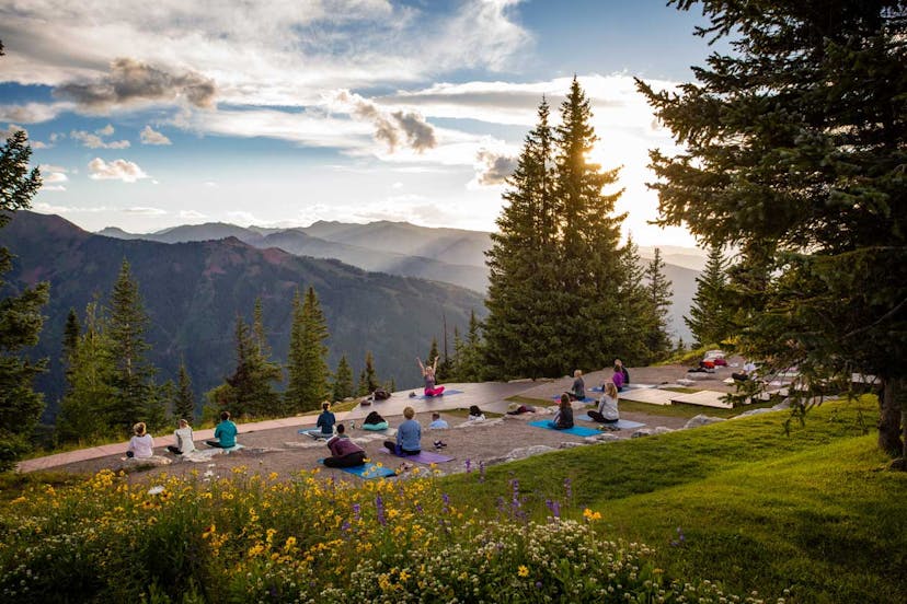 A group of people doing yoga at sunrise on a mountaintop