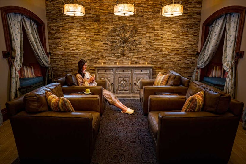 A woman waits in a plush waiting room in a spa robe