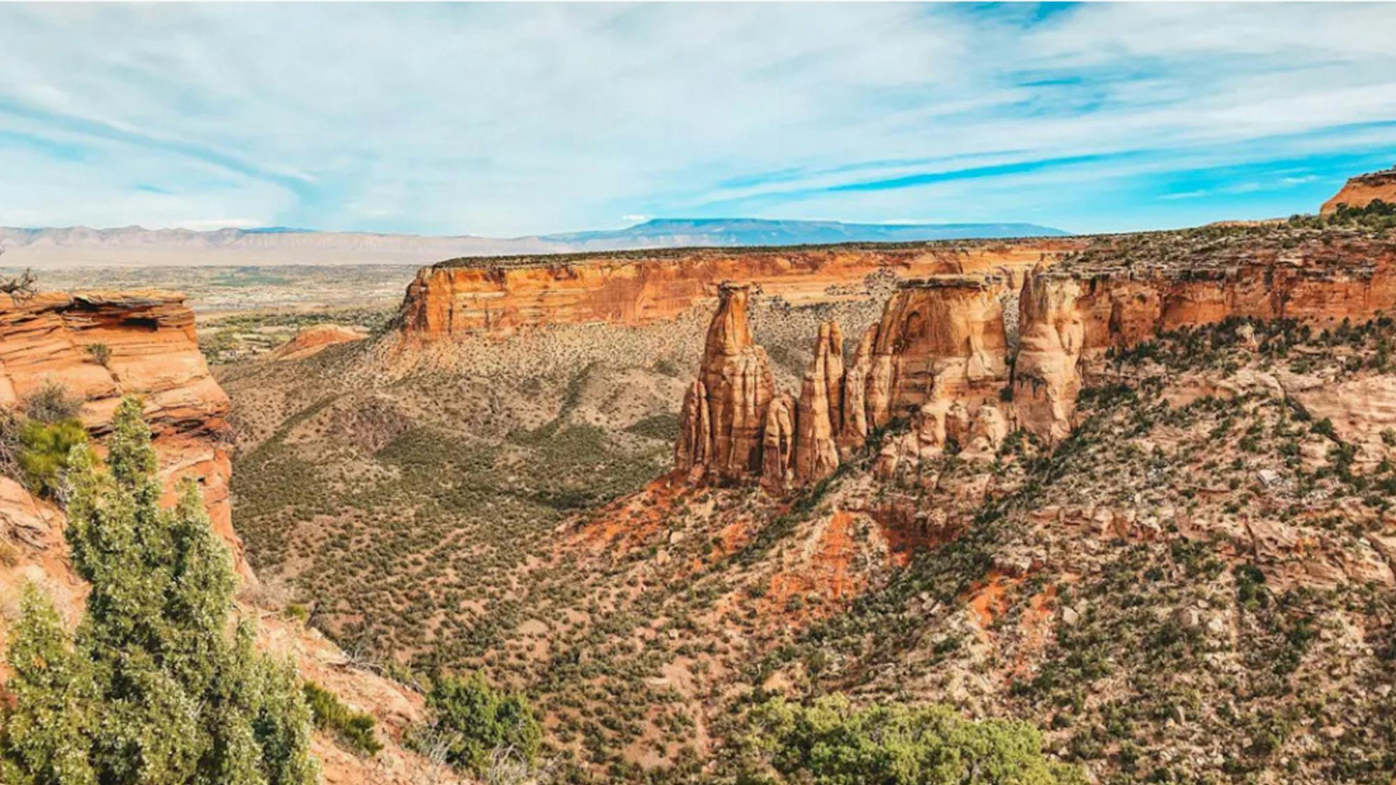 An aerial view of the red-rock spires and juniper-dotted canyons of Colorado National Monument near Grand Junction