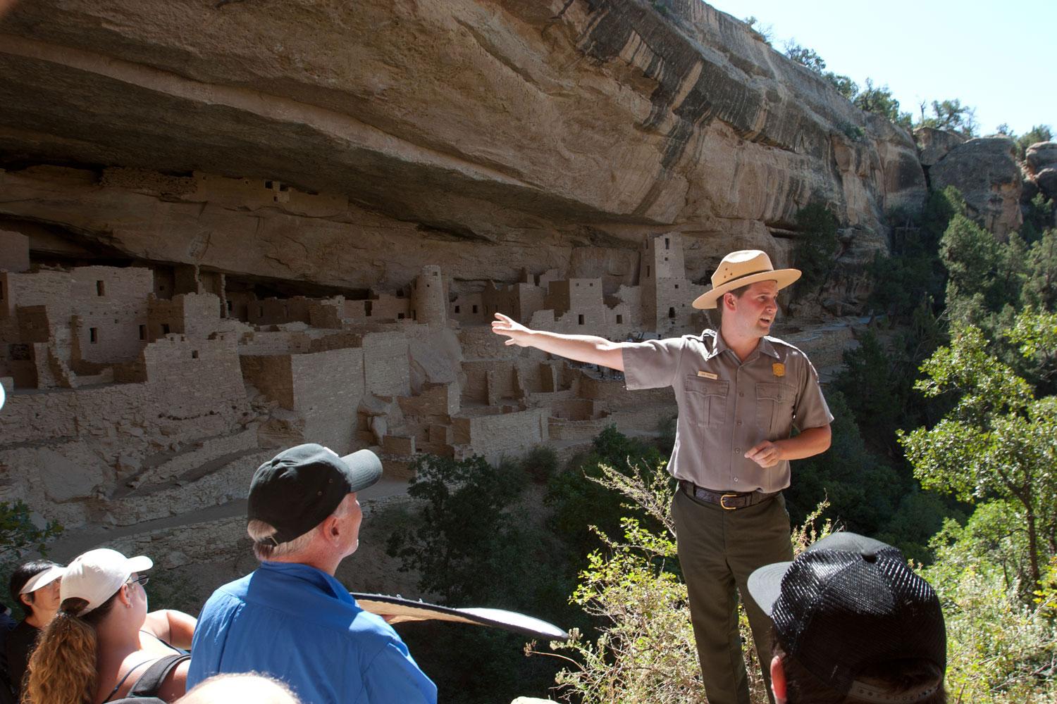 A ranger at Mesa Verde National Park points to cliff dwellings for a tour group