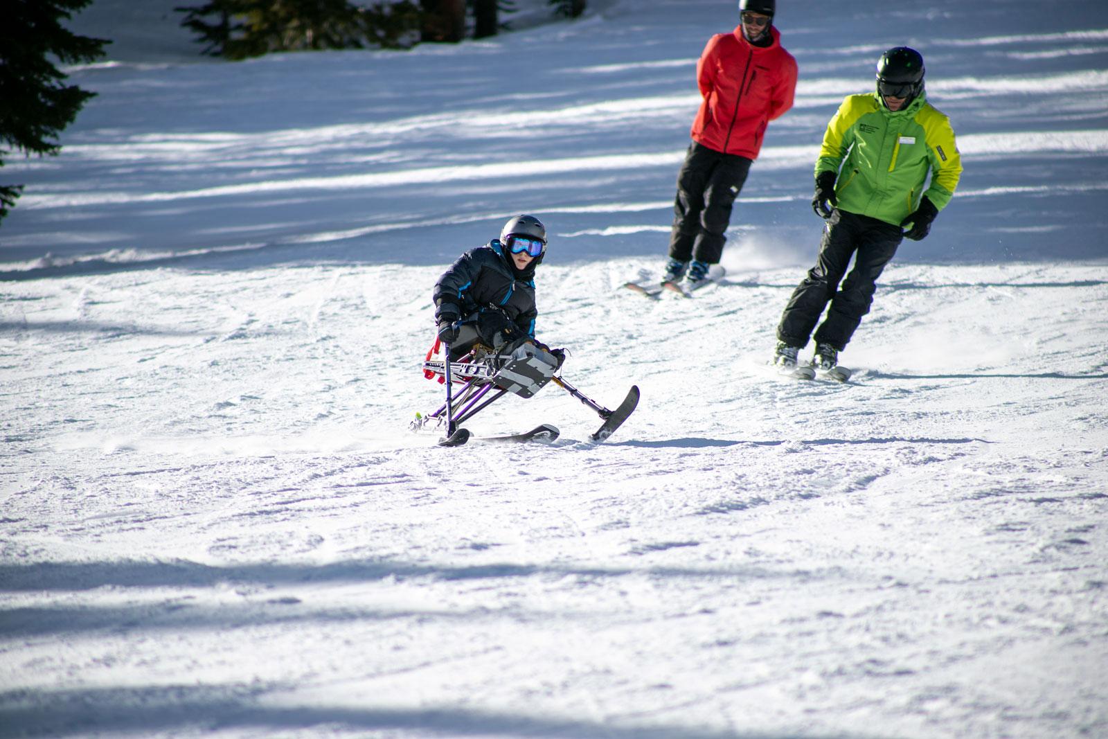 A child sits in an adaptive ski chair and weaves their way across a snowy slopes in Breckenridge, Colorado.