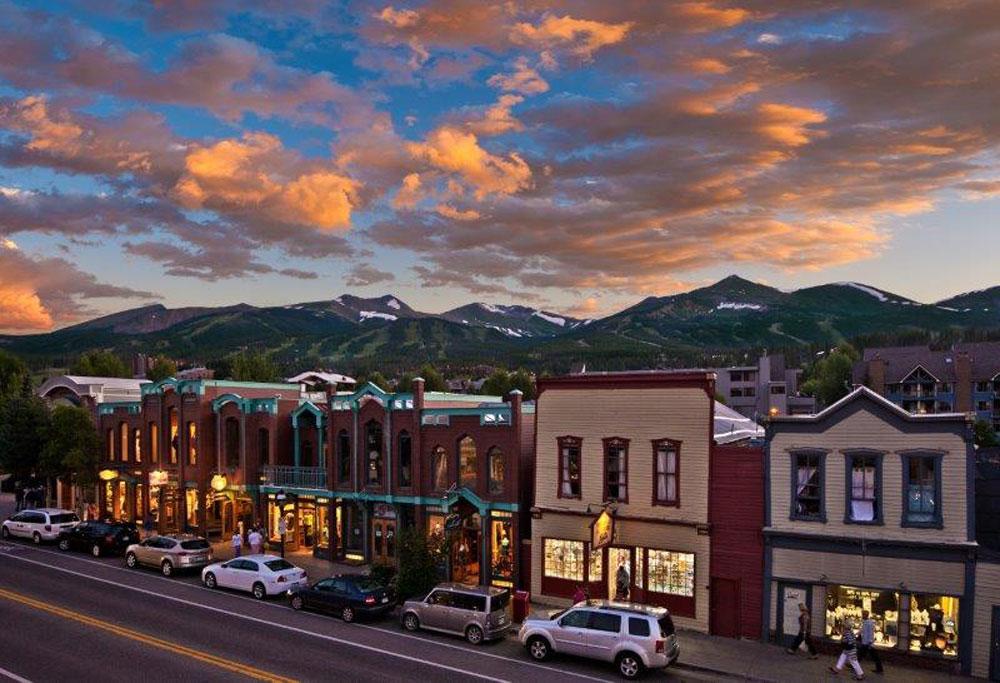 The sun is setting with pink clouds against a blue sky above historic, Western Breckenridge.