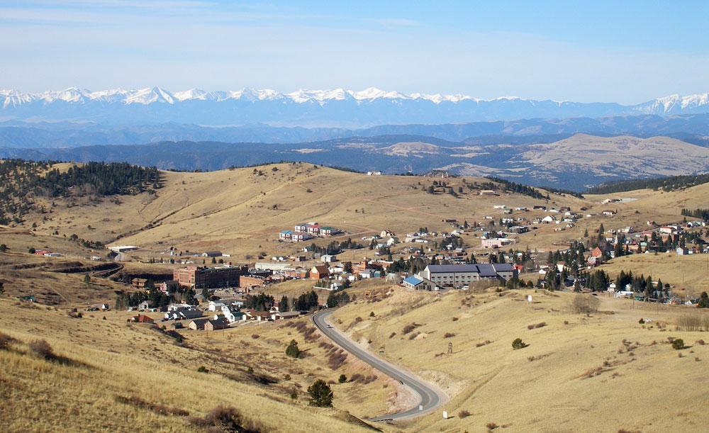 From a scenic overlook, we see the tiny buildings of Cripple Creek with snowcapped mountains in the distance