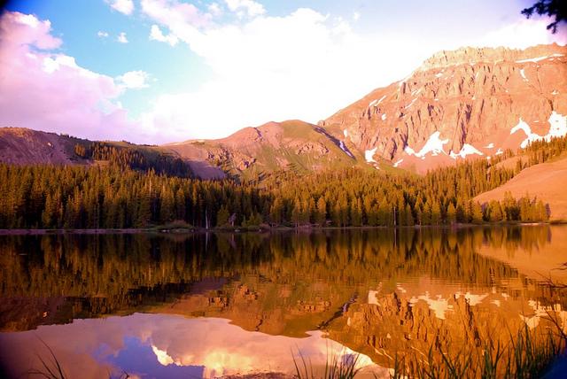 Sunlight reflects on a golden lake with mountains in the background