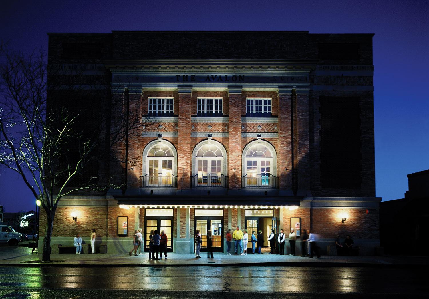 A multi-story brick building is lit up against the dark backdrop of the evening sky in Grand Junction, Colorado.