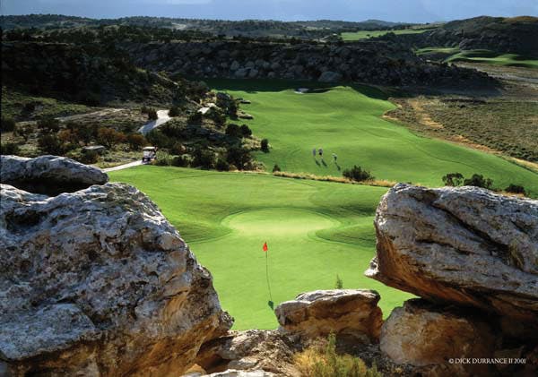 A golf course green in Grand Junction is surrounded by rocky outcroppings. 