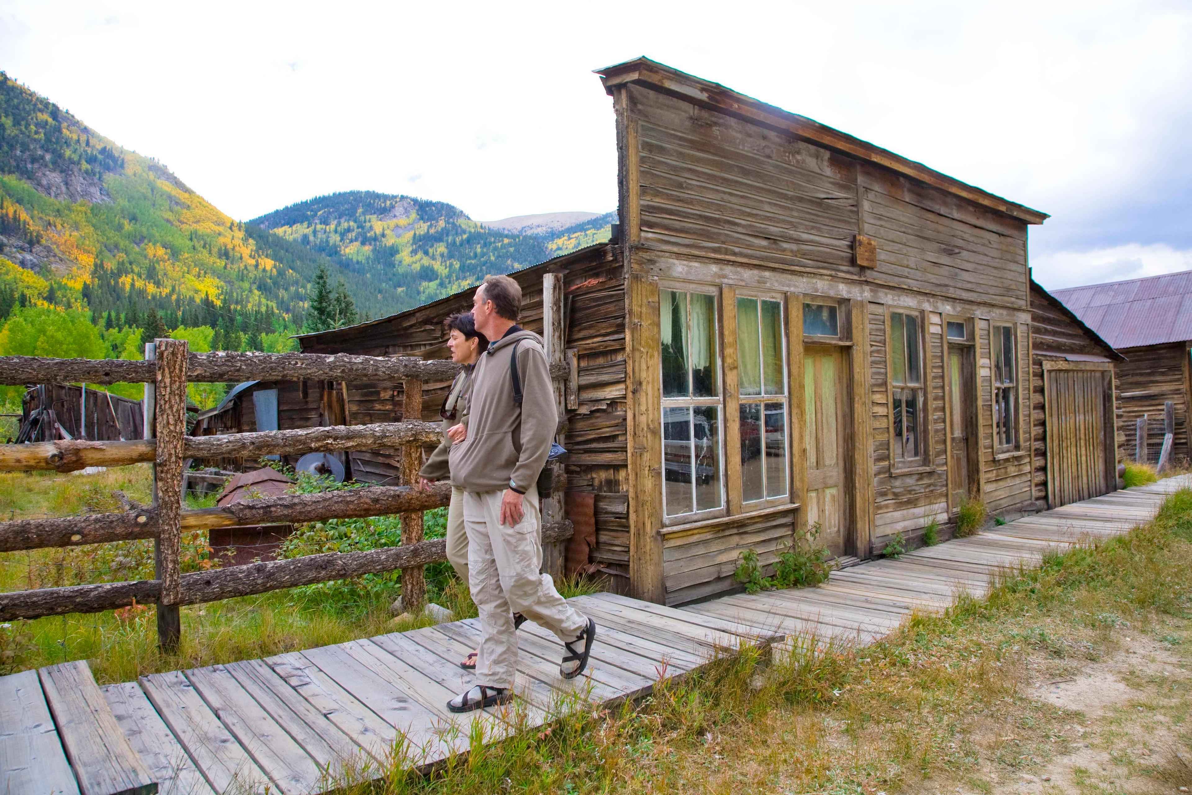 Two hikers dressed in long pants and sweaters roam the abandoned town of St. Elmo, near Nathrop, Colorado.