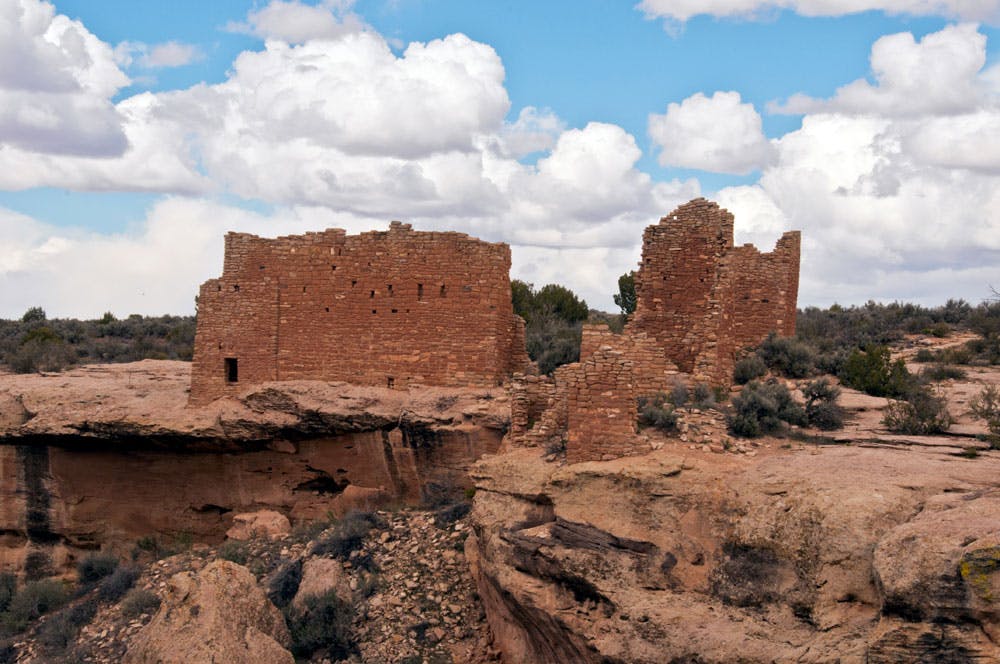 The ruins of two ancient red-clay brick structures stand the test of time amid the rocky cliffs and desert shrubs near Cortez, Colorado.