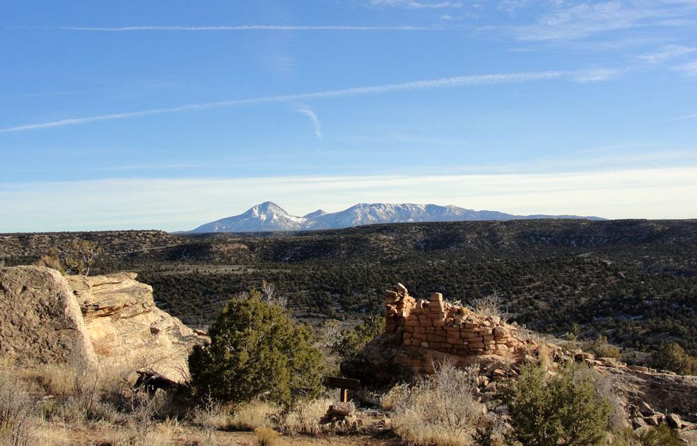 A distant mountain peak lies across a wide green prairie, miles from the ancient ruins at Hovenweep National Monument, near Cortez, CO.