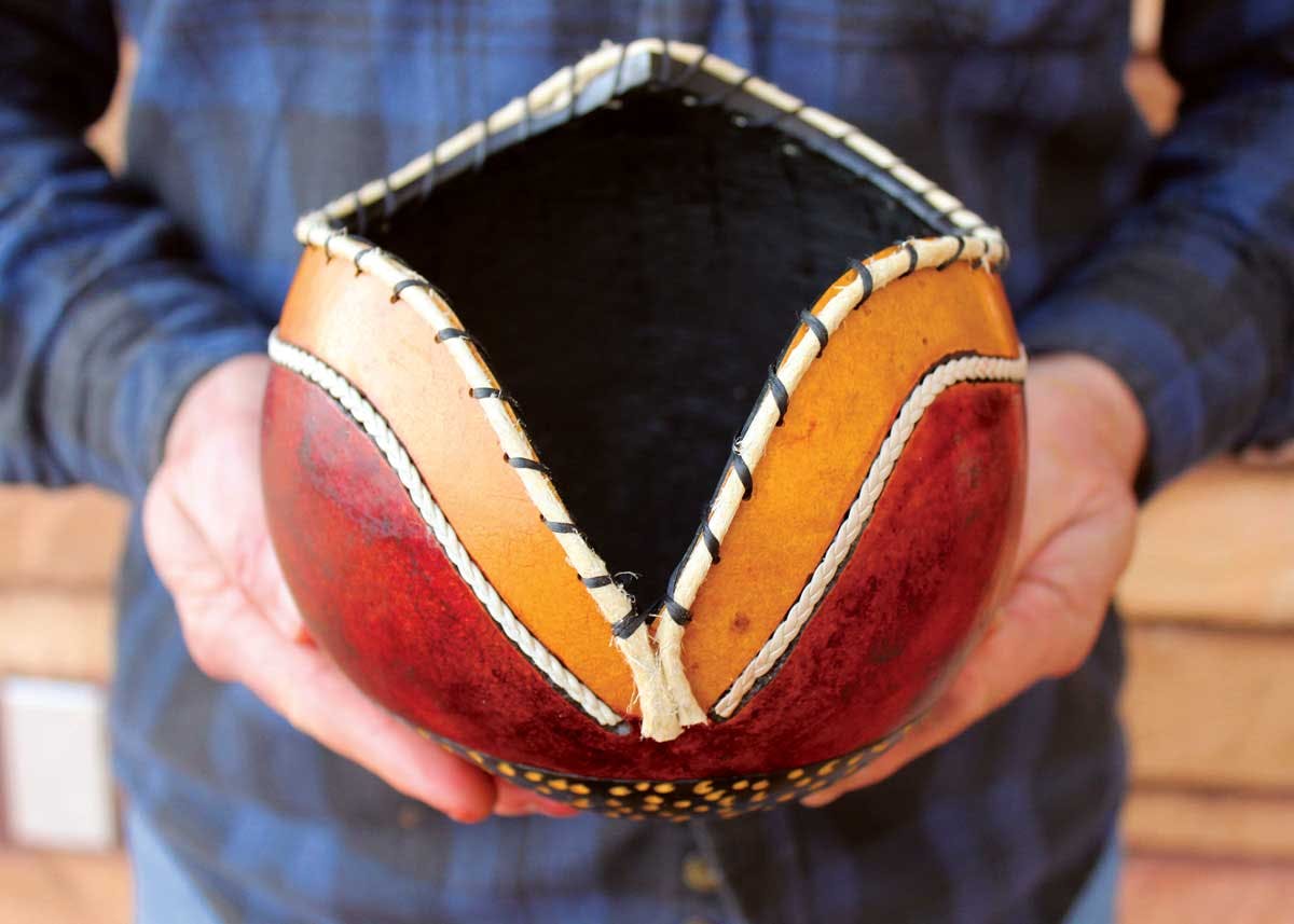 A person holds a homemade, red and orange art piece at Mancos School of the West workshops