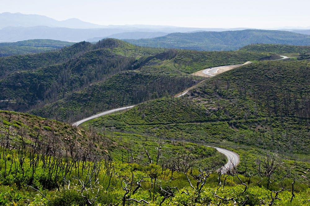 A long road winds through a lush valley and through the mountains