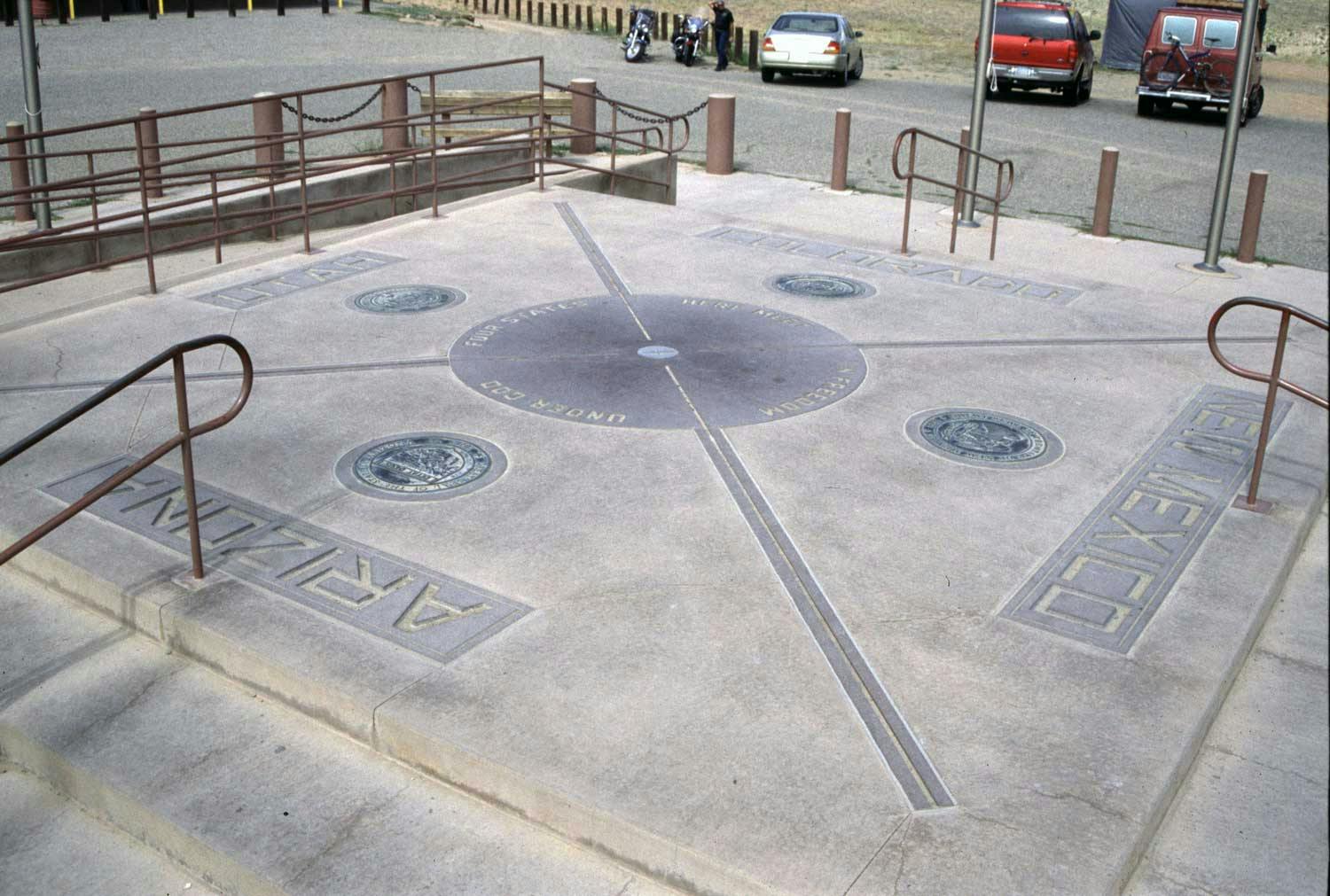 A raised concrete slab engraved with four different state names serves as a landmark known as the Four Corners Monument in Colorado.